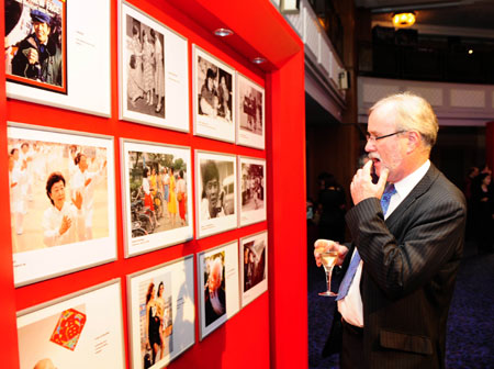 A guest looks at photos showcasing China's achievements during a reception held by the Chinese Embassy to mark the 60th anniversary of the founding of the People's Republic of China, in London, Britain, Sept. 24, 2009. (Xinhua/Zeng Yi)