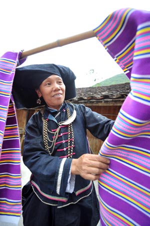 An old woman of Dark Cloth Zhuang dries cloth woven by herself in Napo county, southwest China's Guangxi Zhuang Autonomous Region, Sept. 23, 2009.