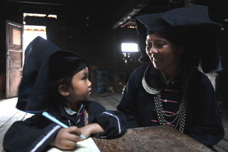 A woman of Dark Cloth Zhuang helps her daughter do homework in Napo county, southwest China's Guangxi Zhuang Autonomous Region, Sept. 23, 2009.