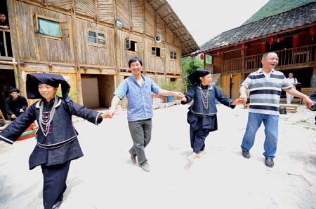 Women of Dark Cloth Zhuang dance with tourists in Napo county, southwest China's Guangxi Zhuang Autonomous Region, Sept. 23, 2009. 