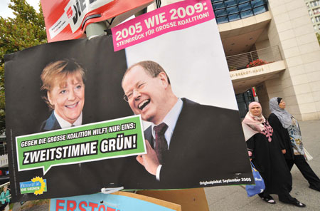 Women pass by an election poster in Berlin, capital of Germany, Sept. 26, 2009. German will vote for general elections on Sunday. (Xinhua/Wu Wei)