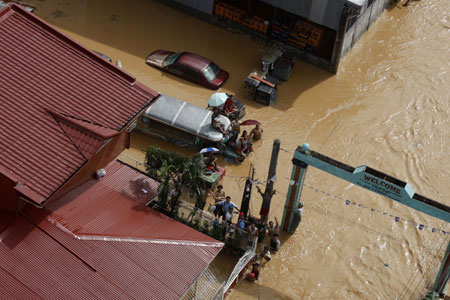 People wait for rescue on the submerged street in Cainta of Rizal Province, the Philippines, on Sept. 27, 2009. At least 51 people were killed while 21 others remain missing as tropical storm Kestana hit the Philippines and brought massive flood on Saturday, the government disasters relief agency said Sunday. (Xinhua/Stringer)