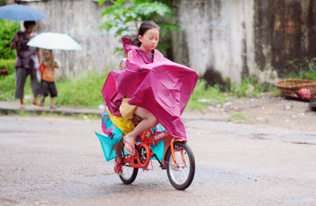 A girl rides bicycle in rain in Qionghai City, south China's Hainan Province, Sept. 28, 2009. [Meng Zhongde/Xinhua]