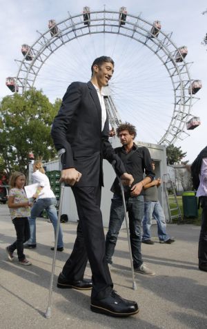 The world's tallest man, Sultan Kosen of Turkey, walks in front of Vienna's Giant Wheel landmark September 27, 2009. Kosen,26, who is 246.5 cm (8 feet 1 inch) tall, also claims the record for the largest hands and feet.