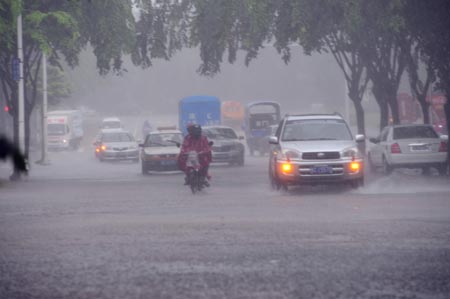 Vehicles trudge ahead against strong rainfalls brought by typhoon Kestana, on the street of Qionghai, south China's Hainan Province, Sept. 29, 2009. [Xinhua]