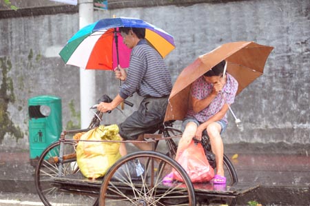 Two persons with umbrellas overhead ride tricycle against strong rainfalls brought by typhoon Kestana, on the street of Qionghai, south China's Hainan Province, Sept. 29, 2009. The typhoon Kestana has affected Qionghai City with continuous gale and brought strong precipitations. Hainan Provincial Meteorologic Bureau has issued orange pre-alert signal against the rainstorm for local administrations to take preventive measures. (Xinhua/Meng Zhongde)