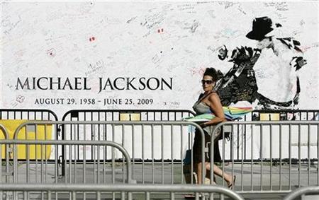 A woman walks past a memorial banner that fans have signed at the L.A. Live complex for the opportunity to purchase tickets for a special showing of the 'Michael Jackson's This Is It' movie in Los Angeles, California, September 25, 2009.