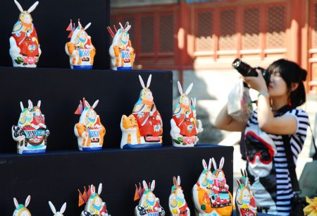 A visitor takes photos of rabbit figurines at the Dongyue Temple in Beijing, capital of China, Oct. 3, 2009, the Mid-Autumn Festival.(Xinhua/Fan Jiashan)