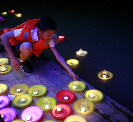 A boy puts an orange lantern into the Yongning River in Taizhou, east China's Zhejiang Province, Oct. 2, 2009.(Xinhua/Zhang Lingting)