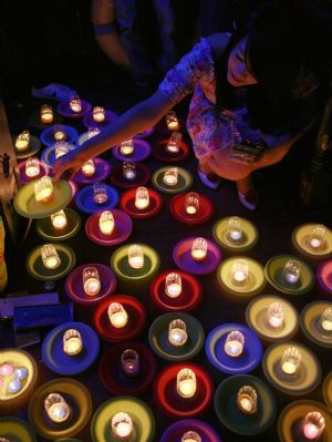 A woman arranges orange lanterns on the bank of Yongning River in Taizhou, east China's Zhejiang Province, Oct. 2, 2009.(Xinhua/Zhang Lingting)