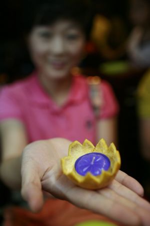 A woman shows an orange lantern on the bank of Yongning River in Taizhou, east China's Zhejiang Province, Oct. 2, 2009.(Xinhua/Zhang Lingting)