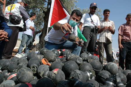 Palestinians, Israelis and foreign demonstrators display the tear gas cases that were fired by Israeli troops during a demonstration against Israel's separation barrier in the West Bank village of Bilin, near Ramallah, on Oct. 9, 2009. [Nidal Eshtayeh/Xinhua]