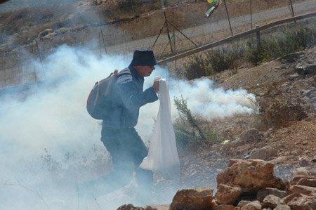 A demonstrator runs from the tear gas fired by Israeli troops during a demonstration against Israel's separation barrier in the West Bank village of Bilin, near Ramallah, on Oct. 9, 2009. [Nidal Eshtayeh/Xinhua]