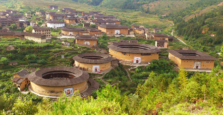 Photo taken on Oct. 5, 2009 shows the Chuxi Tulou, earth buildings in Chinese, in Yongding County, southeast China's Fujian Province. Built on a base of stone, the thick walls of Tulou were packed with dirt and fortified with wood or bamboo internally. The architectural arts of the Fujian Tulou can be traced back nearly 1,000 years, and their design incorporates the tradition of fengshui (favorable siting within the environment). [Yang Xiaoming/Xinhua]