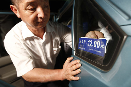 A taxi driver exchanges the price tab of his car in Shanghai, east China, Oct. 11, 2009. Local government increased the start price of taxi fee from 11 to 12 Yuan RMB, while at night the start price reached 16 Yuan RMB. For each additional kilometer the fee is 2.40 Yuan RMB comparing with the original 2.10 Yuan RMB per kilometer. (Xinhua/Pei Xin)