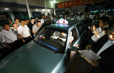 People gather around the taxi that adjusts the taxi fee system in Shanghai, east China, Oct. 11, 2009. (Xinhua/Pei Xin)