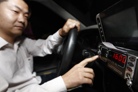 A taxi driver tries to adjust the price meter in his car in Shanghai, east China, Oct. 11, 2009. (Xinhua/Pei Xin)