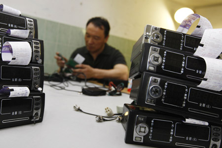 A staff changes the chips for taxi price meters in Shanghai, east China, Oct. 11, 2009. (Xinhua/Pei Xin)