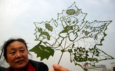 Paper cutting enthusiast Du Wanli shows her leaf carving works during an activity at the Quancheng Plaza in Jinan, capital of east China's Shandong Province, Oct. 11, 2009. Du Wanli made a series of leaf carving works to express her good wishes to the 11th National Games of China which will open in Jinan on Oct. 16, 2009. [Zhao Xiaoming/Xinhua] 