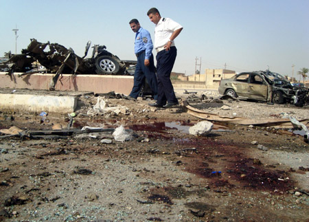 Policemen inspect the site of a twin car bomb in Ramadi, the capital of Anbar province in western Iraq, on October 11. A series of coordinated explosions on Sunday rocked the city of Ramadi, capital of western Iraq's Anbar province, killing 19 people and wounding 81 others. [Xinhua/AFP]