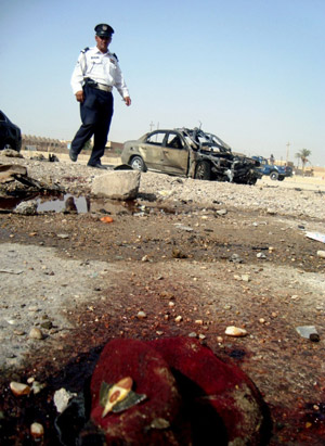 A policeman inspects the site of twin car bombs in Ramadi, the capital of Anbar province in western Iraq, October 11. [Xinhua/AFP]