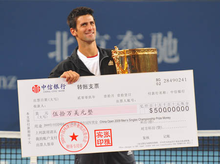 Novak Djokovic of Serbia holds up the trophy and bonus cheque during the awarding ceremony after winning the men's singles final against Marin Cilic of Croatia at the 2009 China Tennis Open Tournament in Beijing, Oct. 11, 2009.[Luo Xiaoguang/Xinhua]