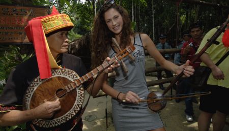  A model plays a Chinese music instrument with a man of local ethnic group in a tourist resort of Baoting in the center of south China's Hainan Province, Oct. 11, 2009.[Xinhua]