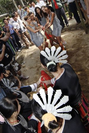 Models play the tug of war with people of China's Li and Miao ethnic groups in a tourist resort of Baoting in the center of south China's Hainan Province, Oct. 11, 2009.[Xinhua]