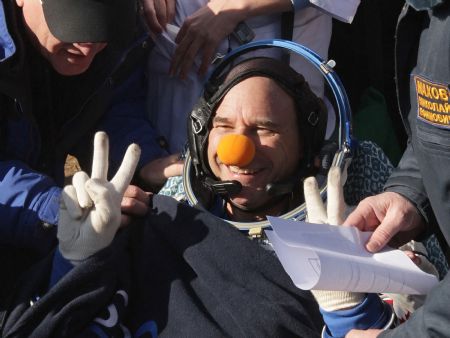 Ground crew members assist Canadian circus billionaire Guy Laliberte (C) after he returned in the Russian Soyuz Space Capsule near the town of Arkalyk, in northern Kazakhstan, October 11, 2009.[Xinhua/Reuters]