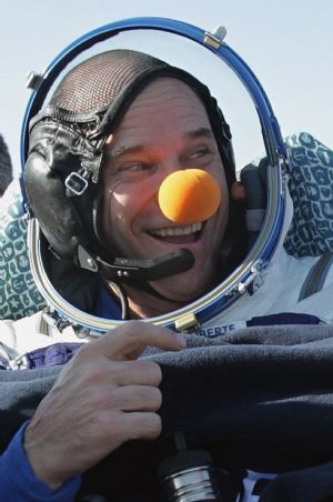 Canadian circus billionaire Guy Laliberte (C) smiles after he returned in the Russian Soyuz Space Capsule near the town of Arkalyk, in northern Kazakhstan, October 11, 2009.[Xinhua/AFP]