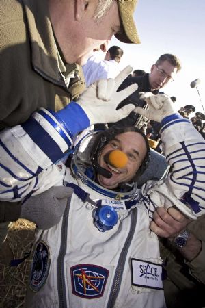 Canadian circus billionaire Guy Laliberte flashes a V-sign after he returned in the Russian Soyuz space capsule near the town of Arkalyk, in northern Kazakhstan, October 11, 2009.[Xinhua/Reuters]