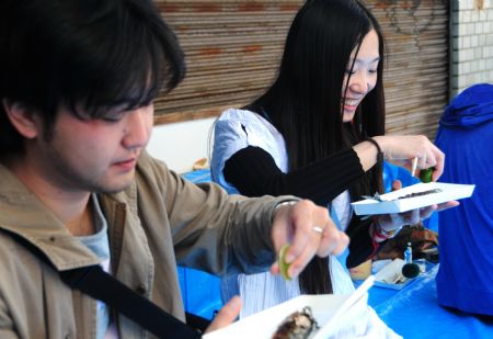 Tourists taste grill saury fish on a street during a saury event in Tokyo, capital of Japan, Oct. 11, 2009.[Hua Yi/Xinhua]