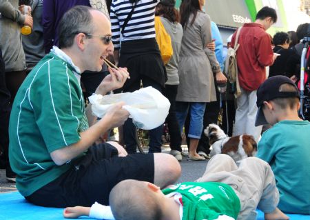 Tourists taste grill saury fish on a street during a saury event in Tokyo, capital of Japan, Oct. 11, 2009.[Hua Yi/Xinhua]