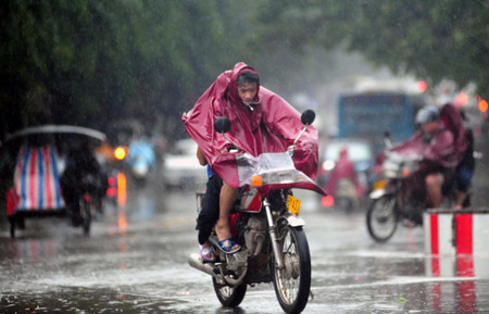 Motorcyclists shrouded in raincoats trudge ahead against gale and downpour on the street of Qionghai City, as the forefront of tropical storm Parma starts to affect south China's Hainan Province, Oct. 12, 2009. According to the Hainan Provincial Meteorologic Bureau, the tropical storm Parma is about to land on Hainan Island on the daytime of October 12. [Meng Zhongde/Xinhua]