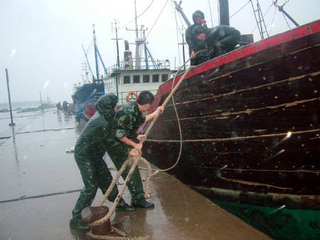 Soilders help the fishermen to fasten the fishing boat in Wenchang City, south China's island Province of Hainan, Oct. 12, 2009.[Huang Ju/Xinhua]