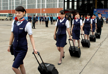 Stewardesses step to board on the florid drawing plane Volunteer of World Expo 2010, during an unveiling ceremony of the plane to mark the 200-day countdown to the World Expo 2010, on the tarmac of Hongqiao Airport, in Shanghai, east China, Oct. 12, 2009. [Huang Guoqing/Xinhua]