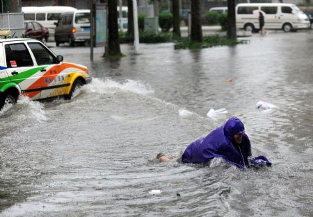 A rider falls to the ground in the heavy winds and rains in Qionghai City, south China's island Province of Hainan, Oct. 12, 2009.(