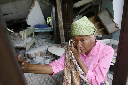 A woman wipes away her tears as she tries to salvage her belongings in her damaged house at Koto Tinggi village in Padang Pariaman October 6, 2009. [China Daily via Agencies]