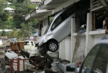 A car hangs from the wall of a building in Pago Pago Harbor after an earthquake caused a tsunami on the island of American Samoa, September 30, 2009. [Agencies]