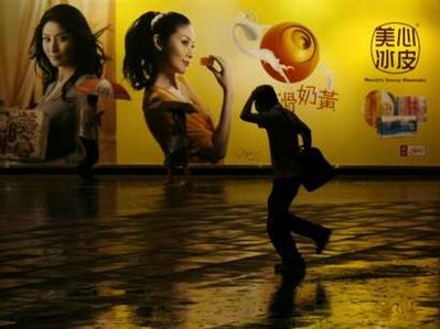 A man runs in rain past an advertising billboard ahead of a typhoon in Hong Kong September 14, 2009.[Agencies]