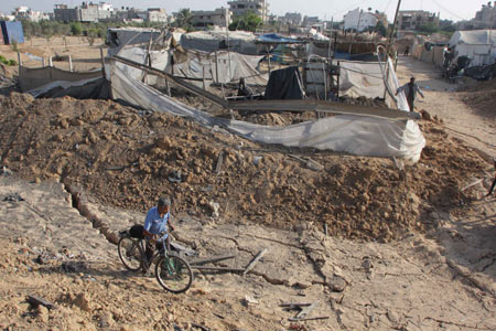 A Palestinian man walks past the entrance to a smuggling tunnel following an Israeli airstrike in Rafah near the border between Egypt and the southern Gaza Strip on October 14, 2009. [Khaled Omar/Xinhua]
