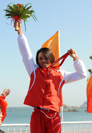 Wang Yi from Shandong Province waves to the spectators during the awarding ceremony for the women's triathlon at the China's 11th National Games in Weihai City, east China's Shandong Province, Oct. 14, 2009.[Li Gang/Xinhua]