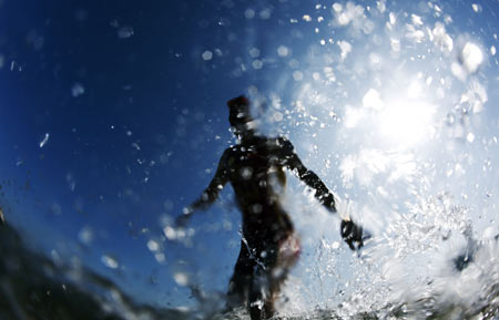 An athlete comes out from the sea during the swim segment in the women's triathlon at the China's 11th National Games in Weihai City, east China's Shandong Province, Oct. 14, 2009. [Fei Maohua/Xinhua]