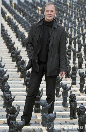 German artist Ottmar Hoerl stands in between plastic garden dwarves as part of his art installation 'Dance with the Devil' in the main square in Straubing, south eastern Germany October 14, 2009. [icpress.cn]