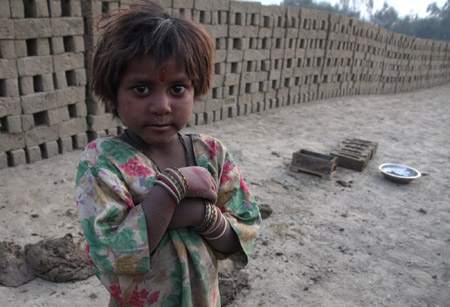 An Indian migrant child laborer looks at the photographer at a brick kiln in Brakpora Anantnag, some 65 kilometers south of Srinagar, summer capital of Indian controlled Kashmir, Oct. 16, 2009. [Javed Dar/Xinhua Photo]