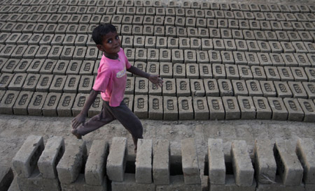 An Indian migrant child laborer walks at a brick kiln in Brakpora Anantnag, some 65 kilometers south of Srinagar, summer capital of Indian controlled Kashmir, Oct. 16, 2009. [Javed Dar/Xinhua Photo]