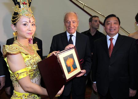 Tai Lihua (L), head of China Disabled People's Performing Art Troupe, presents a gift to Israeli President Shimon Peres before the opening of 'Experience China in Israel' cultural event formally in Tel Aviv Opera House, Oct. 17, 2009.[Xinhua]
