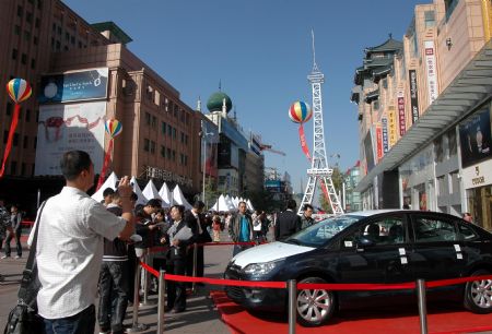 Several visitors gather around an exhibited car produced by the Sino-French joint venture Dongfeng Citroen, during the slated from October 10th to 18th, on the Wangfujing Street, in downtown Beijing, Oct. 17, 2009. More than a dozen French enterprises in Beijing showcase the various feature aspects of French Culture in terms of cuisine, coffee, wine, automobile, and other industrial products, to appeal to Chinese spectactors.[Li Wenming/Xinhua]