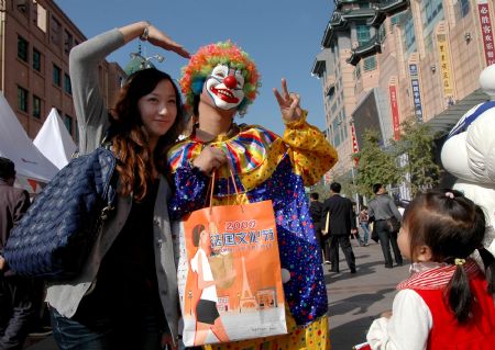 A young woman poses for a photo with a buffoon during the 2009 French Cultural Festival slated from October 10th to 18th, on the Wangfujing Street, in downtown Beijing, Oct. 17, 2009.[Li Wenming/Xinhua] 