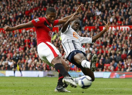 Manchester United's Antonio Valencia (L) shoots past Bolton Wanderers' Fabrice Muamba (R) to score during their English Premier League soccer match in Manchester, northern England, October 17, 2009. Manchester United wins with 2-1.[Xinhua/Reuters]